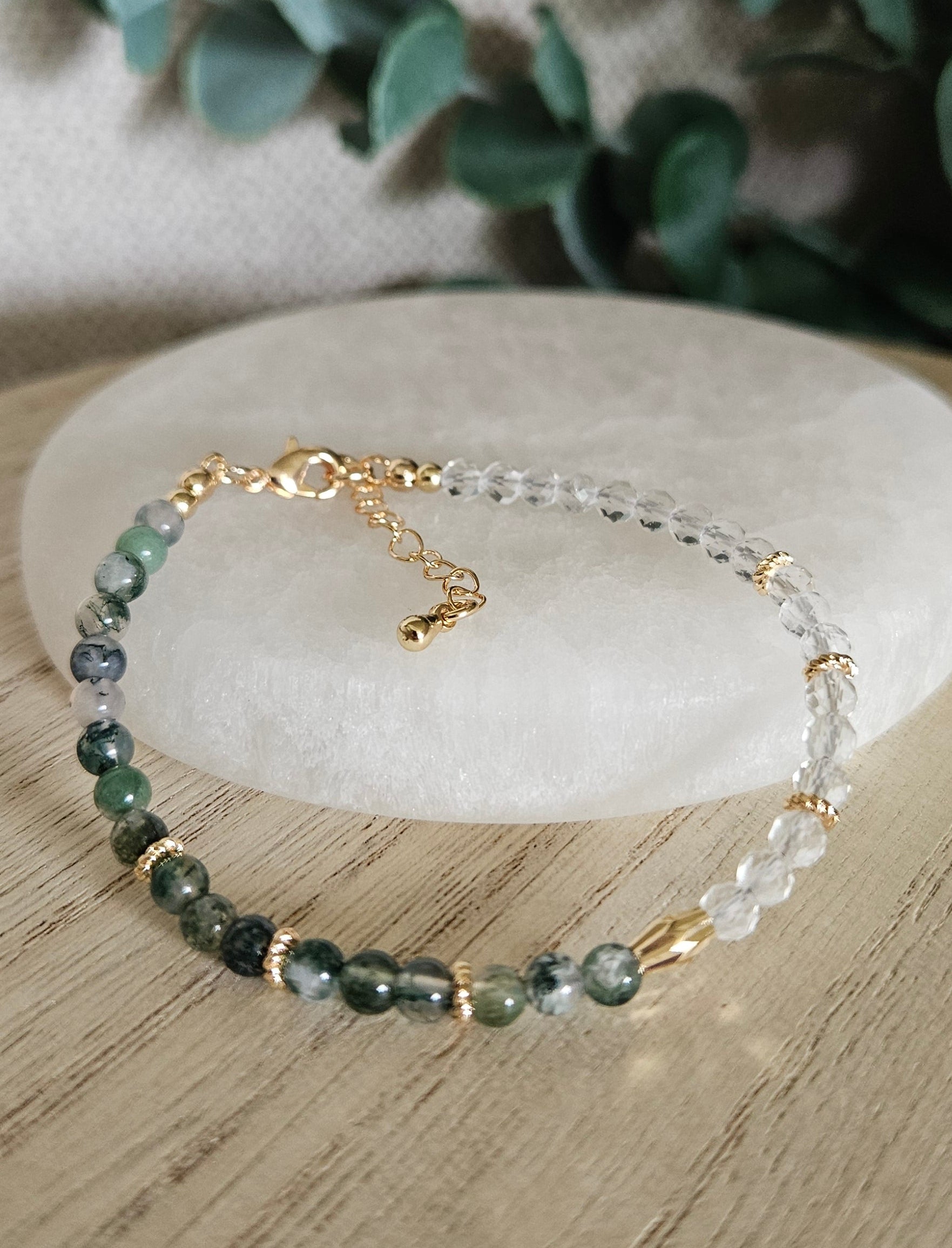 Moss Agate and Clear Quartz bracelet arranged before a selenite plate with eucalyptus in the background