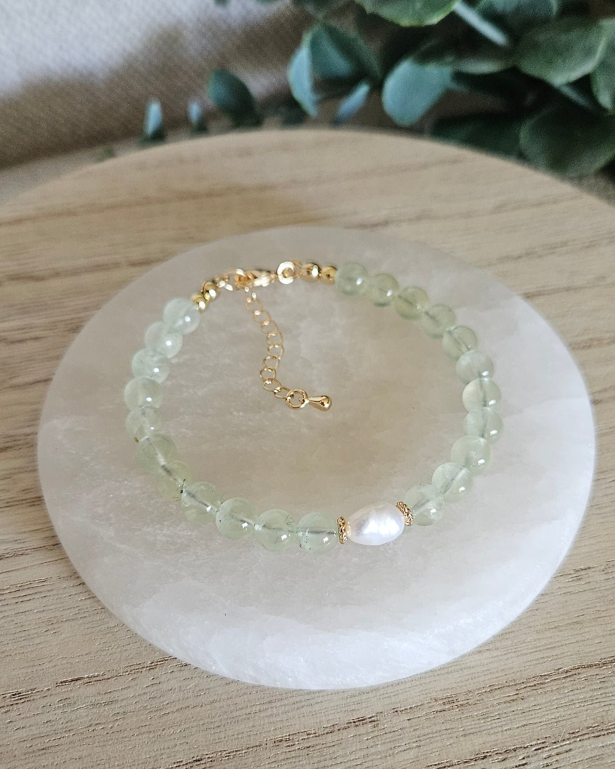 Overhead view of the Prehnite Embrace bracelet with freshwater pearl focal, 14k gold-plated extender chain and soft green gemstone beads on selenite