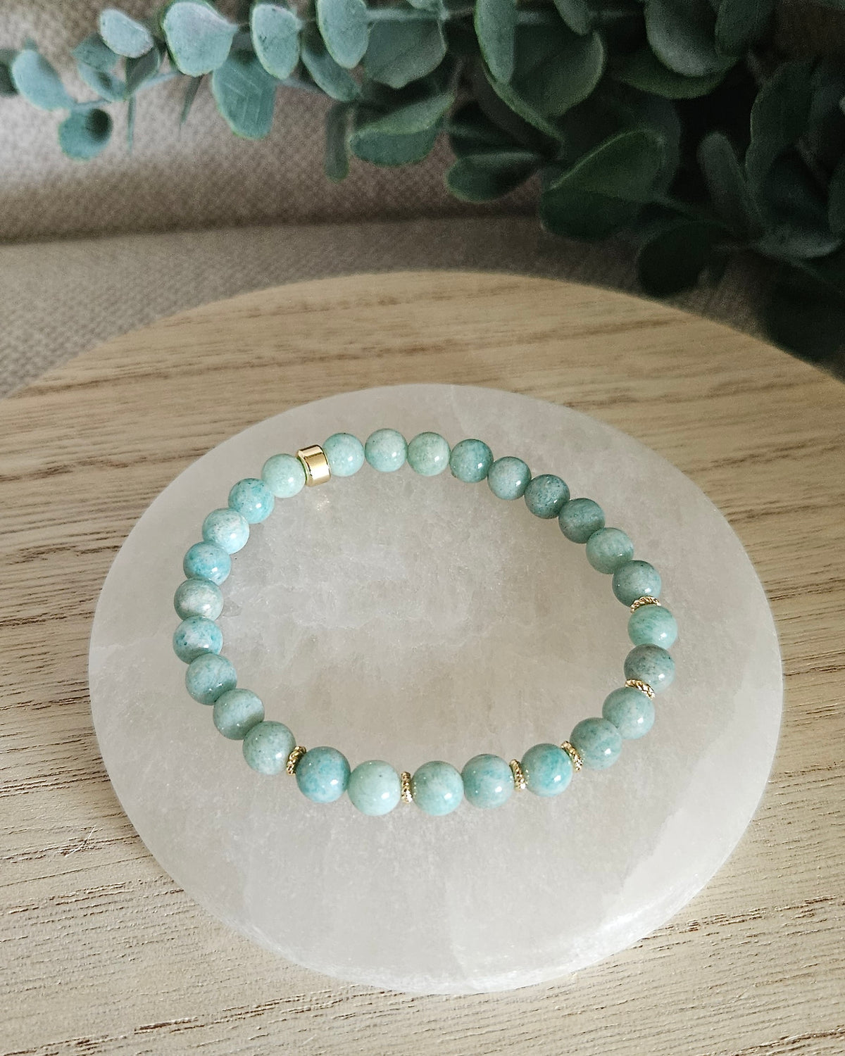 Overhead view of the Amazonite Grace bracelet with soft blue-green beads and gold-plated focal accent on a white selenite plate
