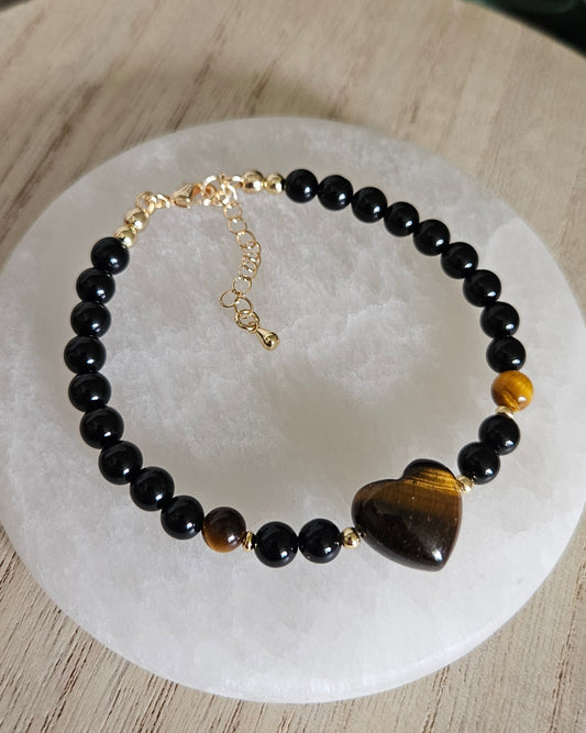 Overhead view of the Black Onyx bracelet with Tiger's Eye heart focal, accent beads and gold extender chain on selenite