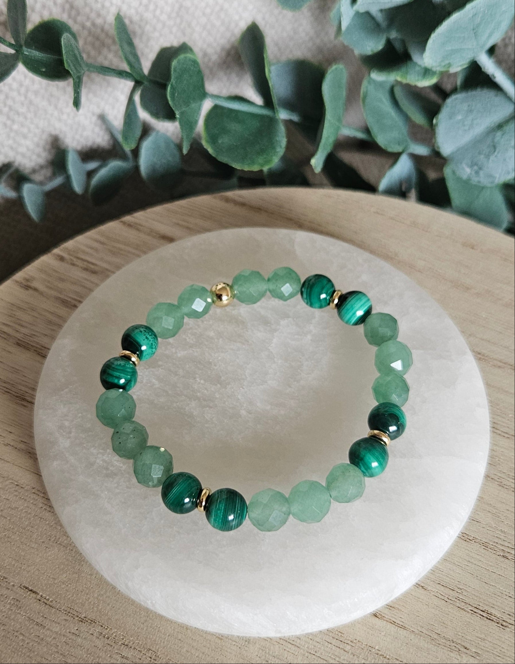 Overhead view of the Green Aventurine and Malachite bracelet arranged on a round selenite plate