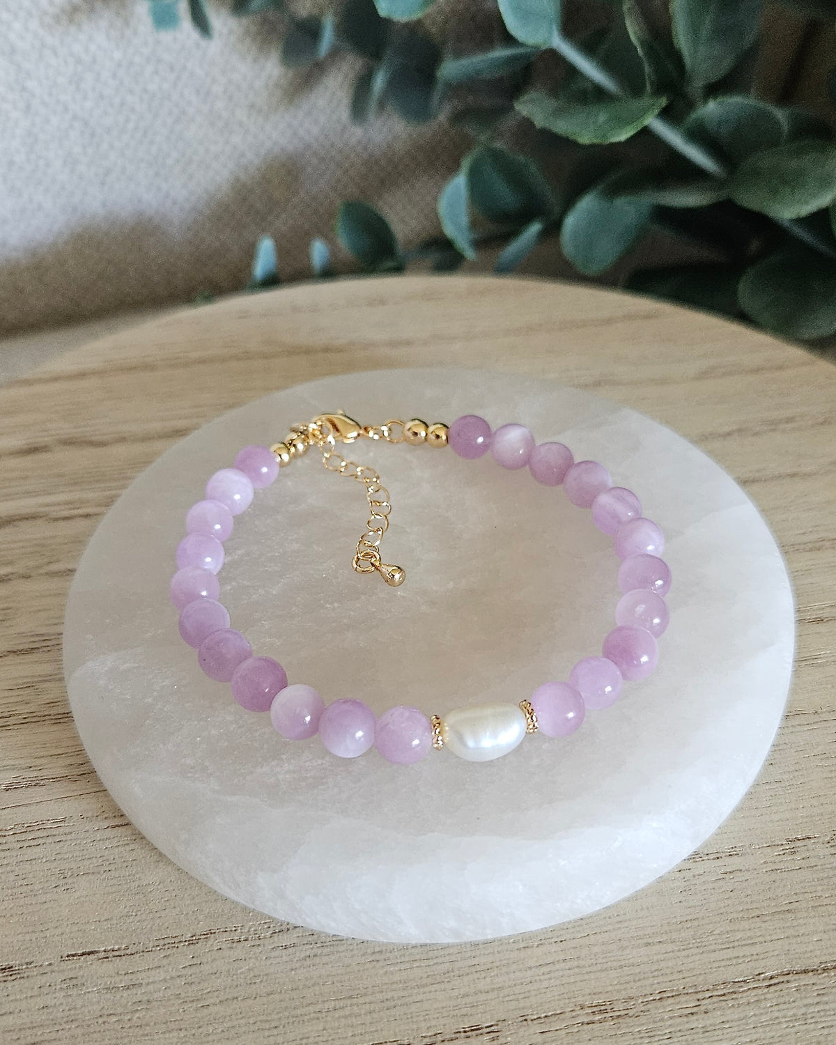 Overhead view of the Kunzite and freshwater pearl bracelet with 14k gold-plated spacers, clasp and extender chain on selenite