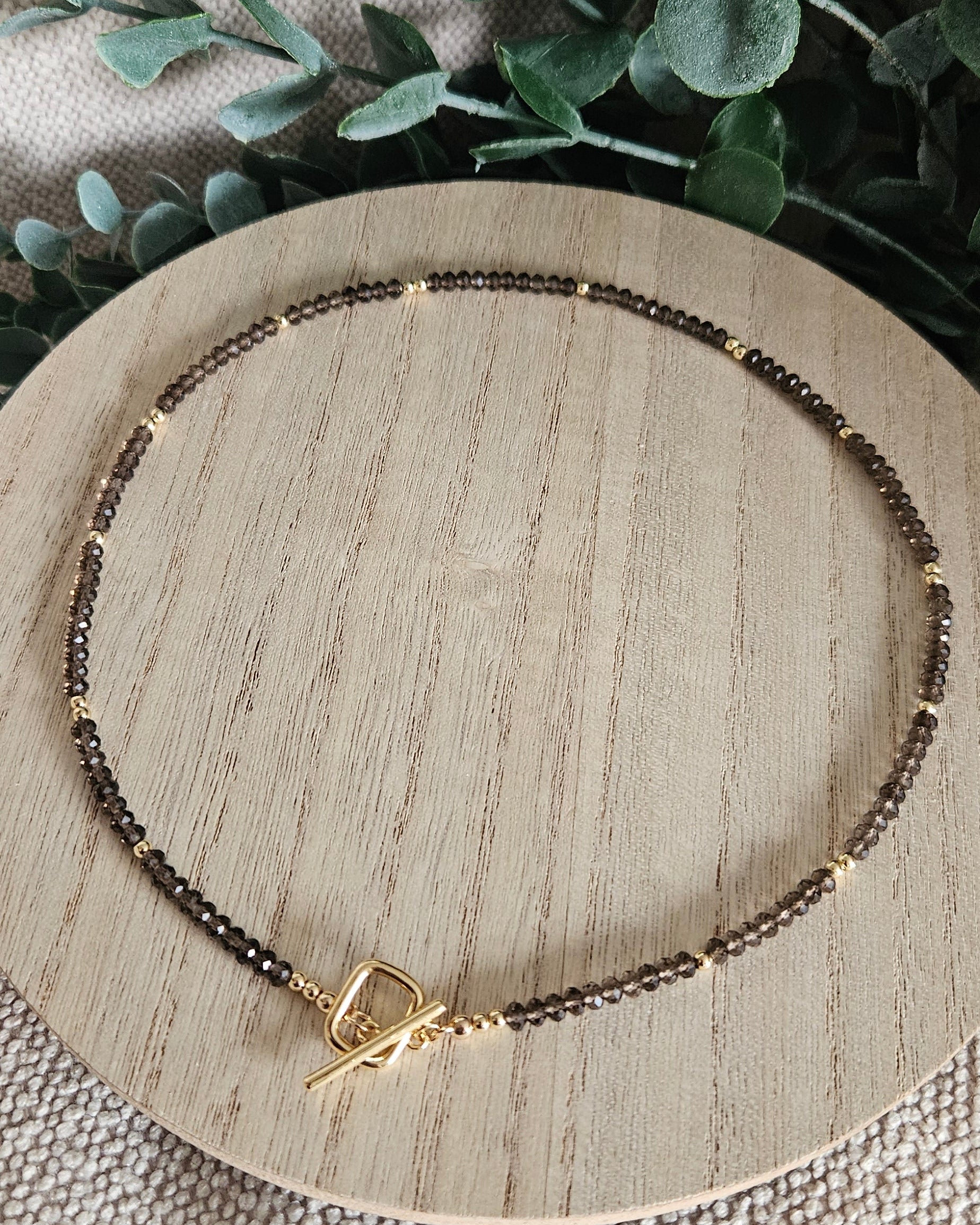 Overhead view of the complete 18-inch Smoky Quartz necklace arranged on a round wooden display