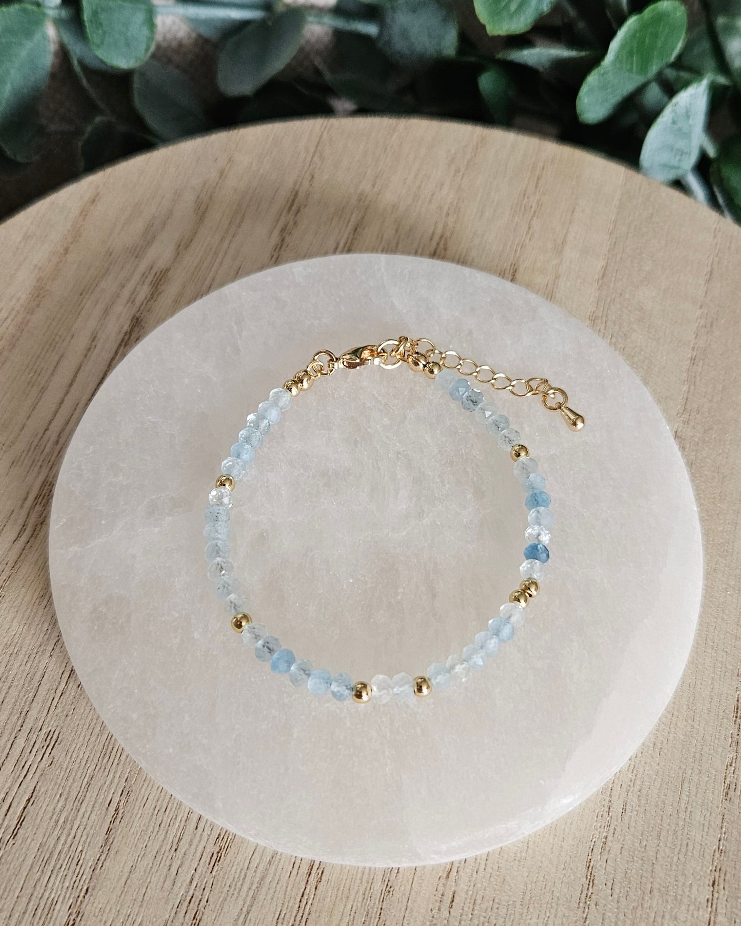 Overhead view of the adjustable Aquamarine rondelle bracelet with gold-plated clasp and extender chain