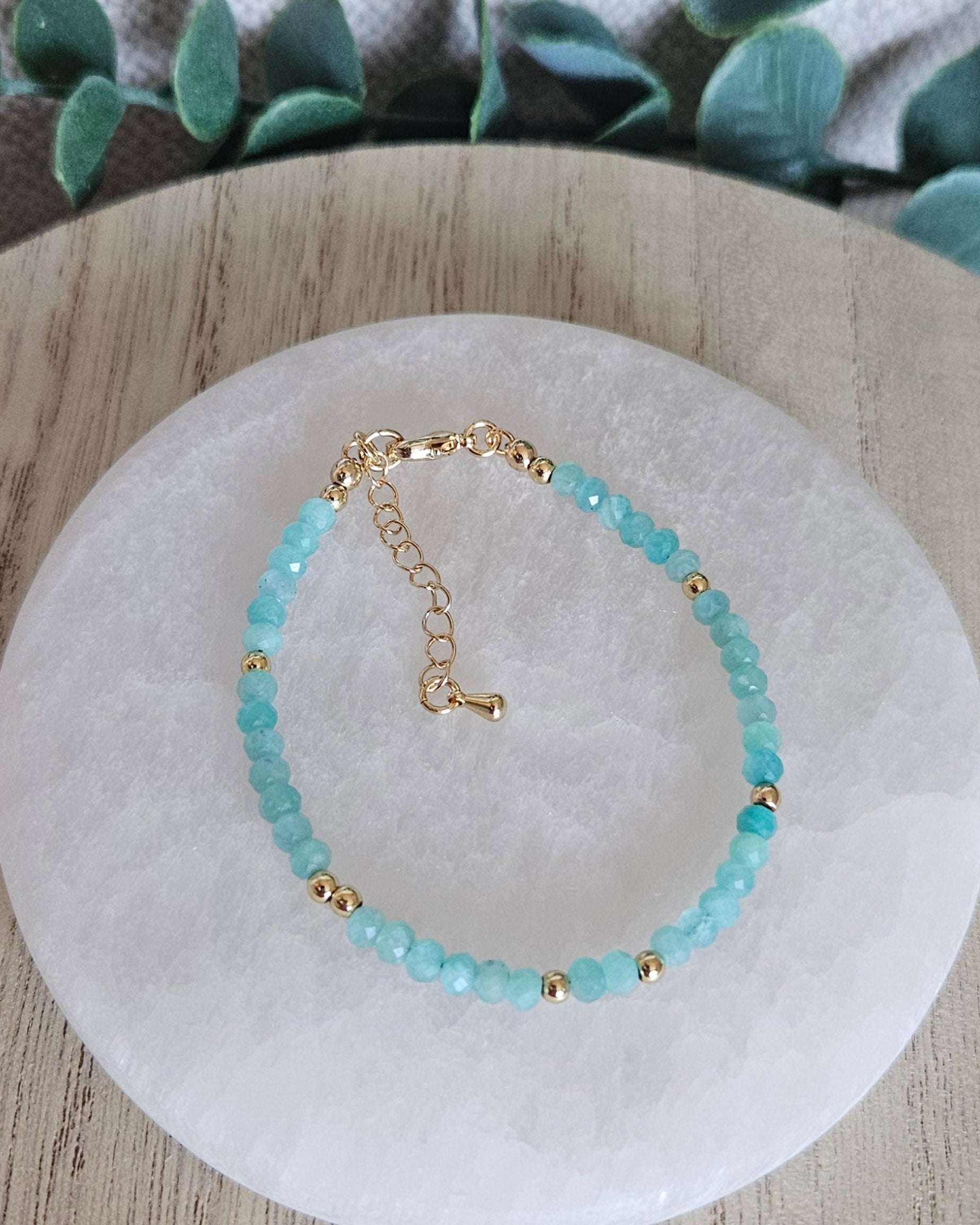 Overhead view of the adjustable Mozambique Amazonite bracelet arranged on a round selenite plate