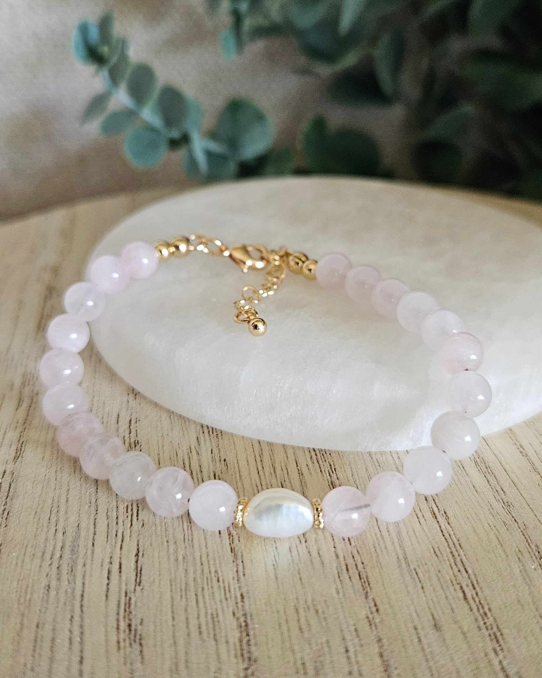 Rose Quartz Embrace bracelet arranged before a selenite plate with a freshwater pearl focal and eucalyptus background