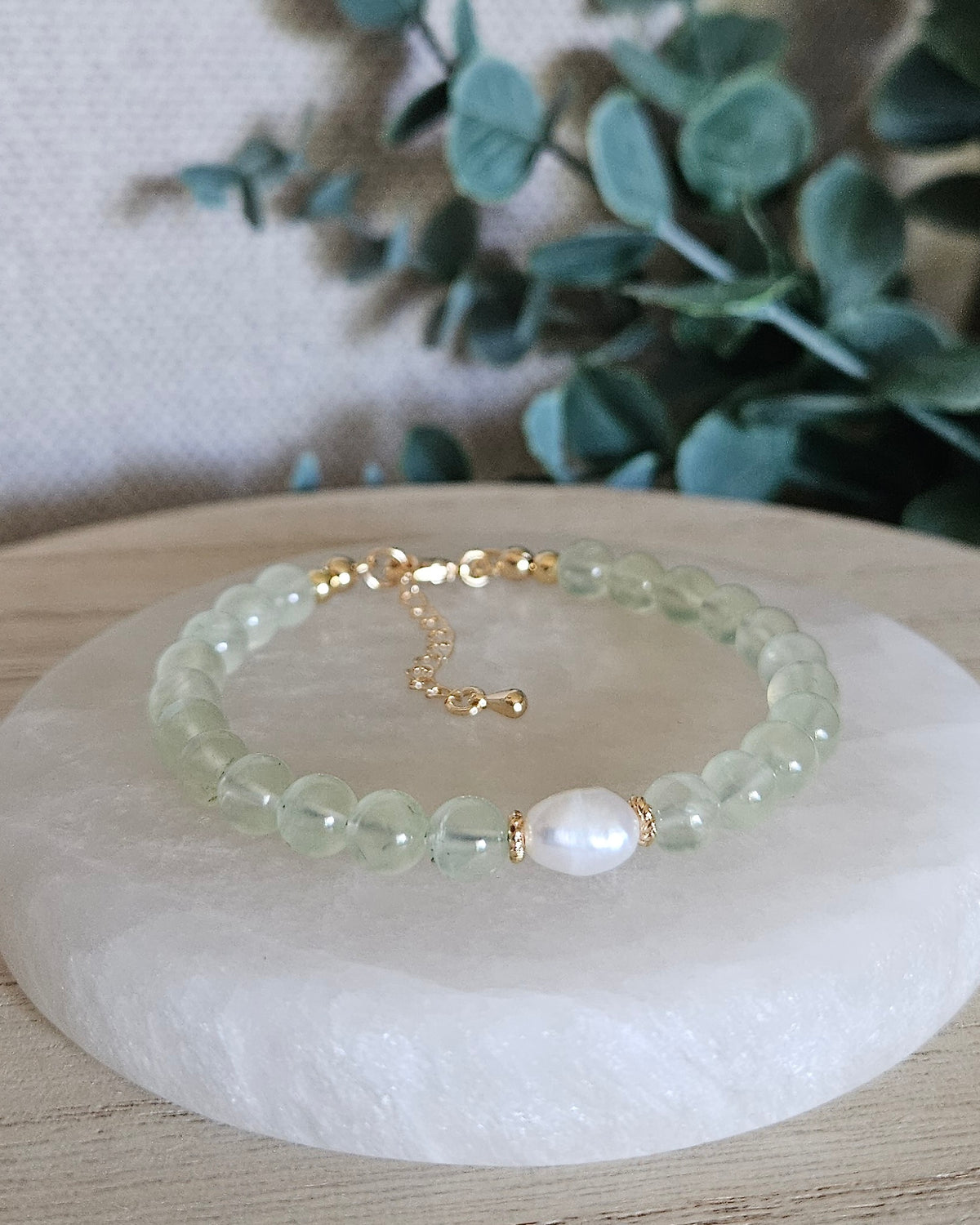 Prehnite Embrace bracelet with 6mm soft green beads, freshwater pearl focal, 14k gold-plated accents and extender chain displayed on selenite