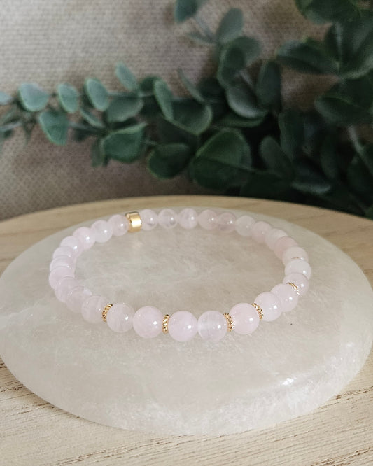 Rose Quartz Grace bracelet with 6mm pale pink gemstone beads and 14k gold-plated accents displayed on selenite