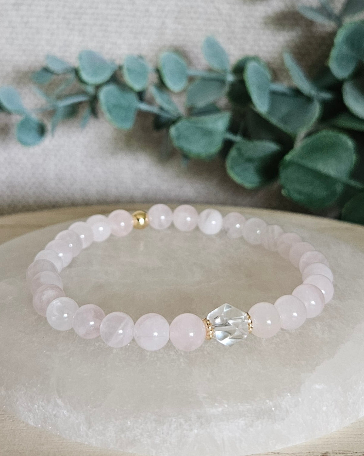 Rose Quartz Still bracelet with 6mm soft pink gemstone beads, Clear Quartz hexagon focal and 14k gold-plated accents displayed on selenite