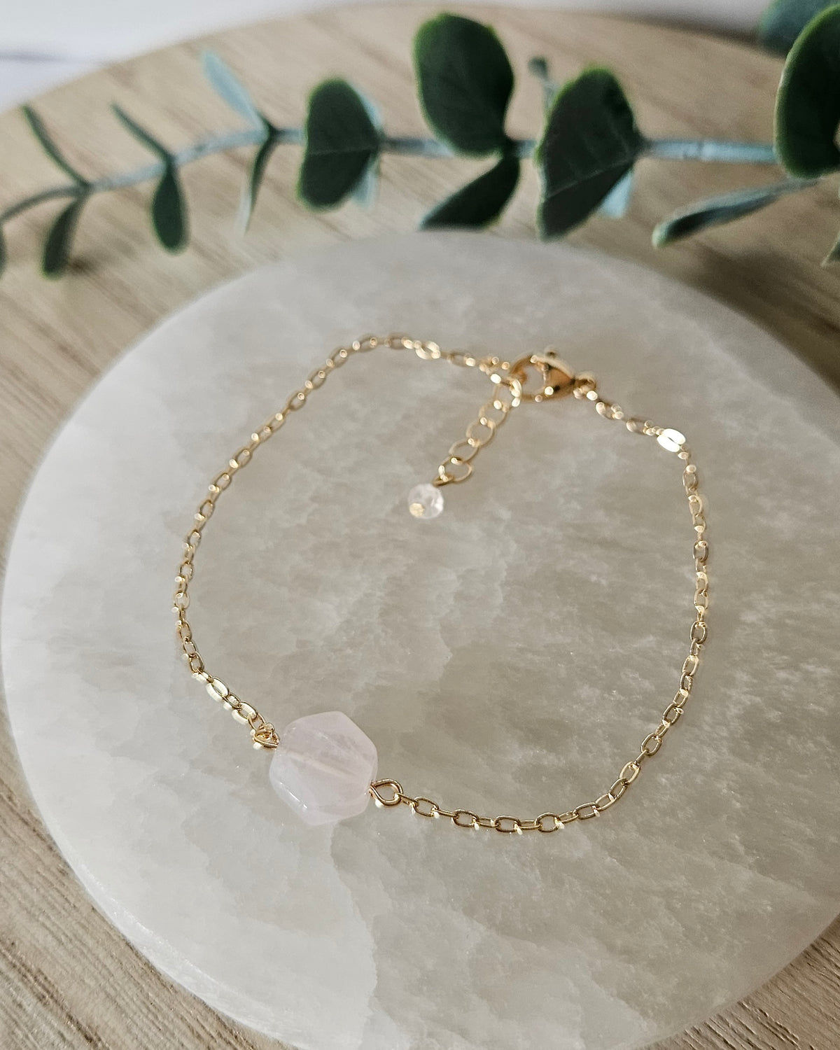 Rose Quartz Whisper bracelet laid flat on a selenite plate with 14k gold-plated chain, clasp and extender