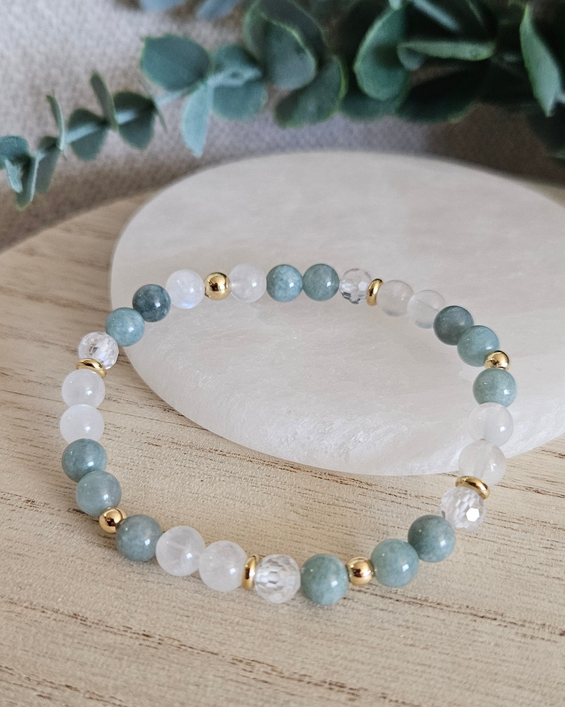 Sage Green Jade and Moonstone bracelet arranged before a selenite plate with Cubic Zirconia and gold accents