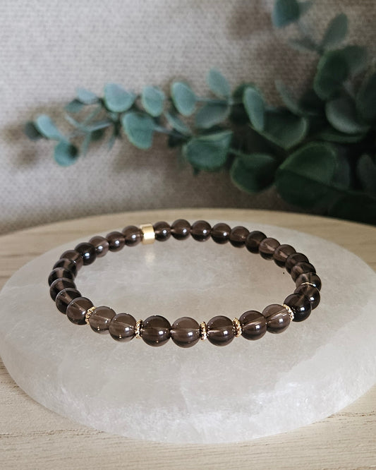 Smoky Quartz Grace bracelet with translucent brown gemstone beads and 14k gold-plated accents displayed on selenite