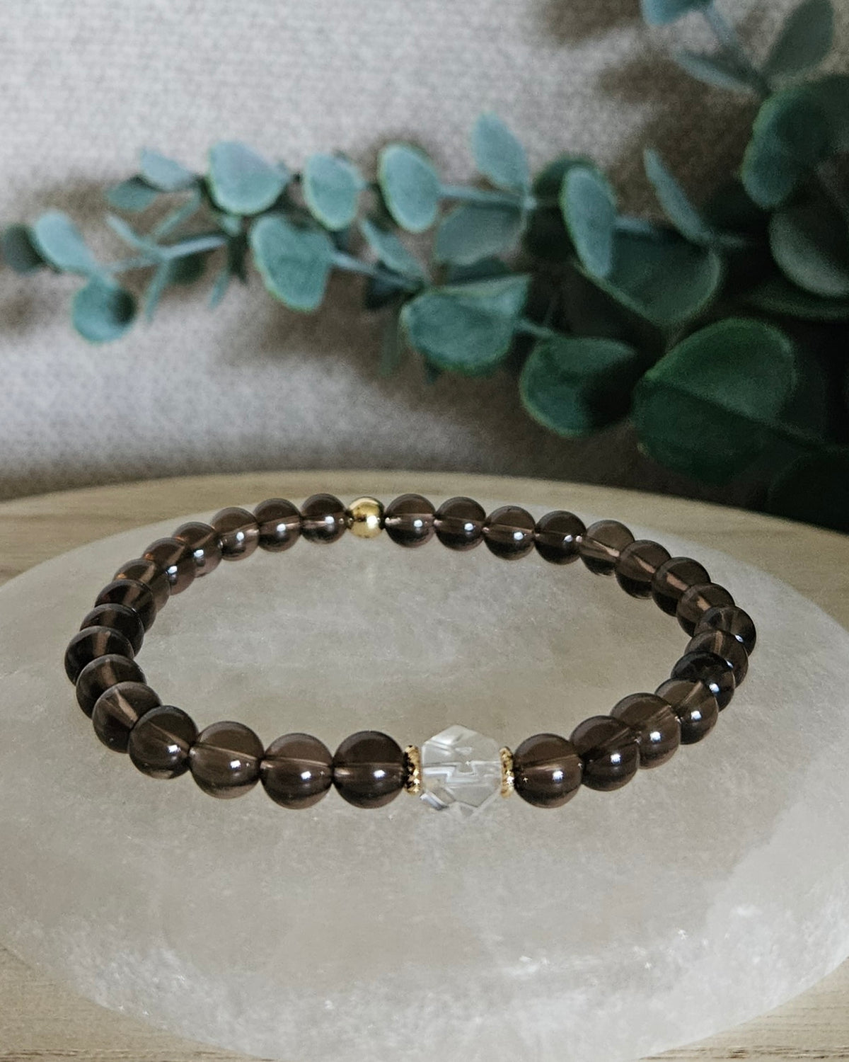 Smoky Quartz Still bracelet with 6mm translucent brown gemstone beads, Clear Quartz hexagon focal and 14k gold-plated accents displayed on selenite