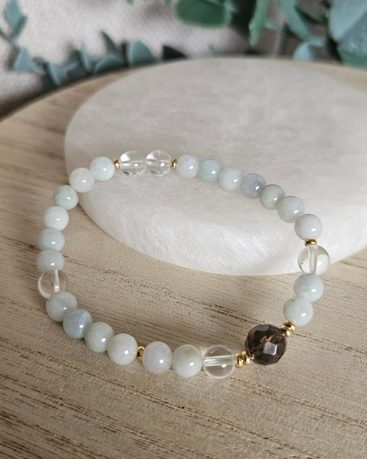 Still Point bracelet arranged before a selenite plate, showing Burmese Jade, Clear Quartz and Smoky Quartz