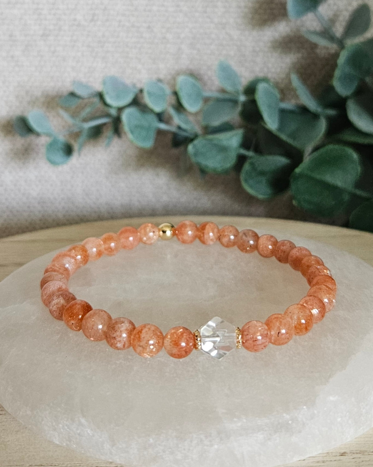 Sunstone Still bracelet with 6mm orange gemstone beads, Clear Quartz hexagon focal and 14k gold-plated accents displayed on selenite