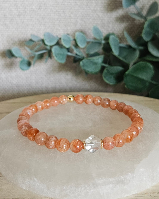 Sunstone Still bracelet with 6mm orange gemstone beads, Clear Quartz hexagon focal and 14k gold-plated accents displayed on selenite