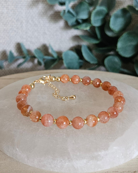 Sunstone Echo bracelet with gold-plated accents and clasp displayed on a round selenite plate