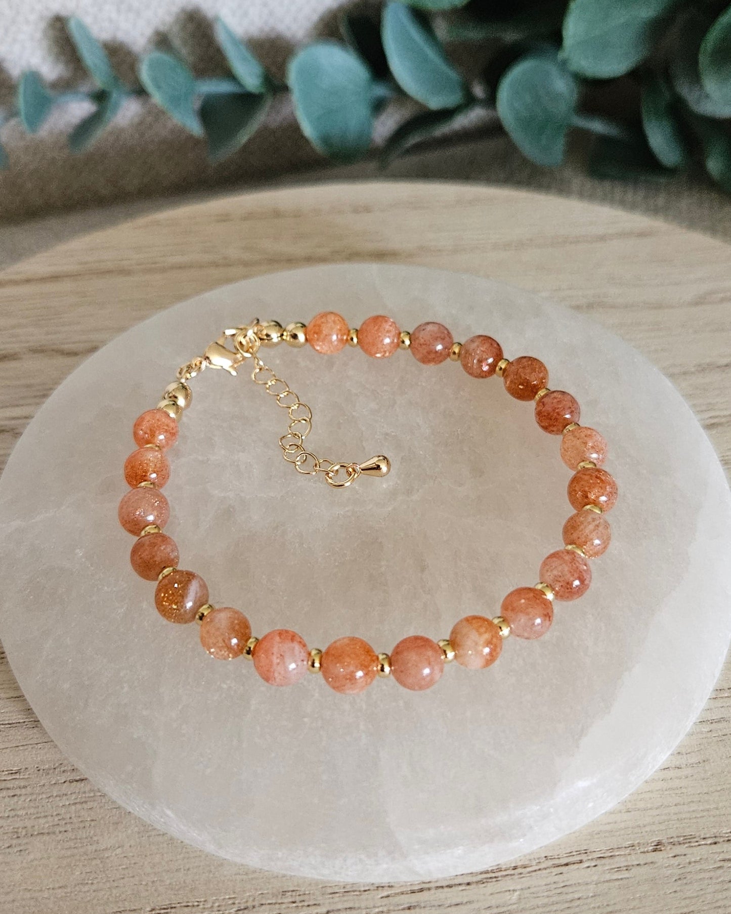 Overhead view of the Sunstone Echo bracelet with gold-plated clasp and extender chain on selenite