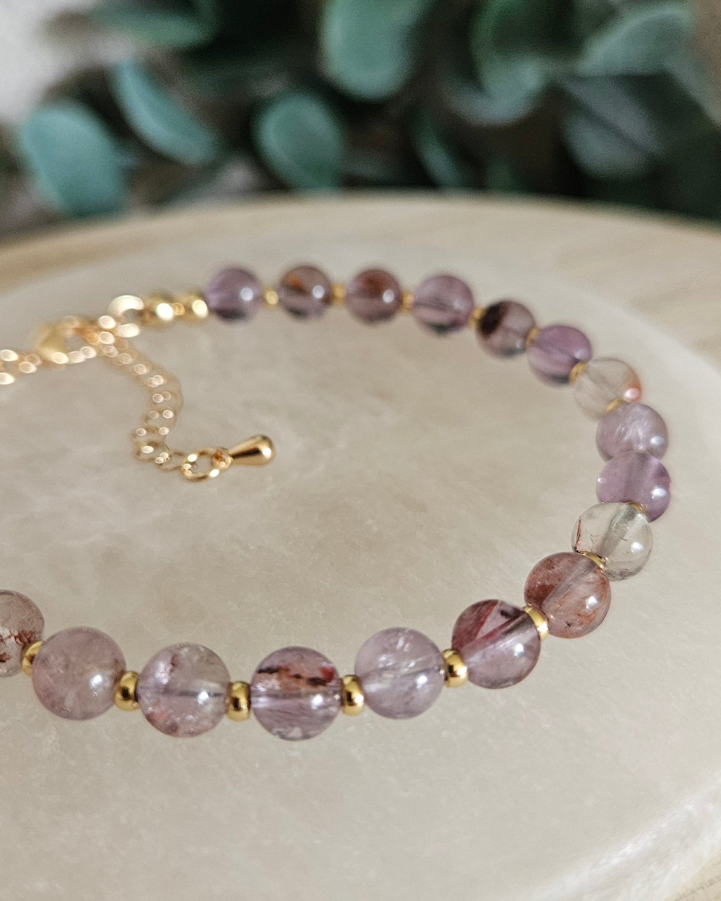 Close-up of glossy Super Seven beads and gold-plated spacers on the Echo bracelet