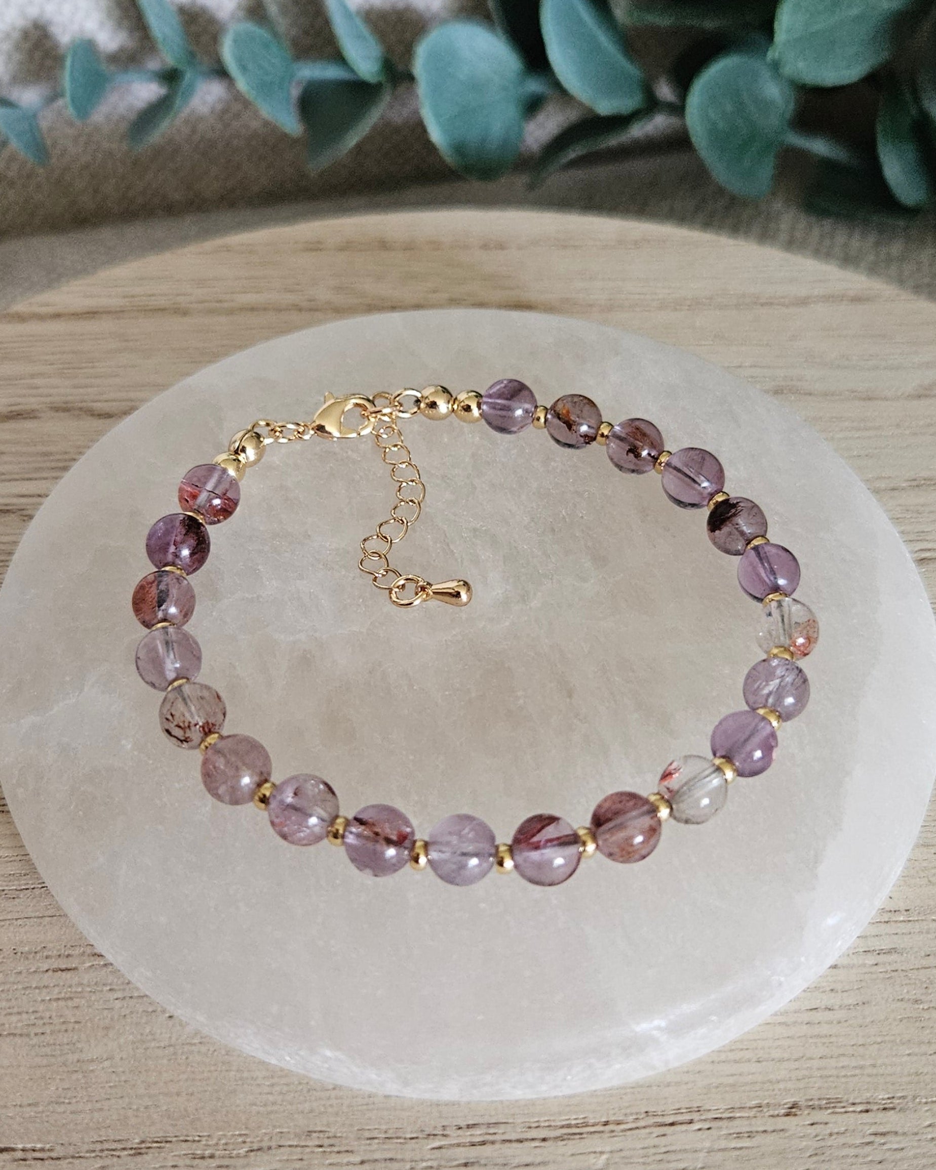 Overhead view of the Super Seven Echo bracelet with gold-plated clasp and extender chain on selenite
