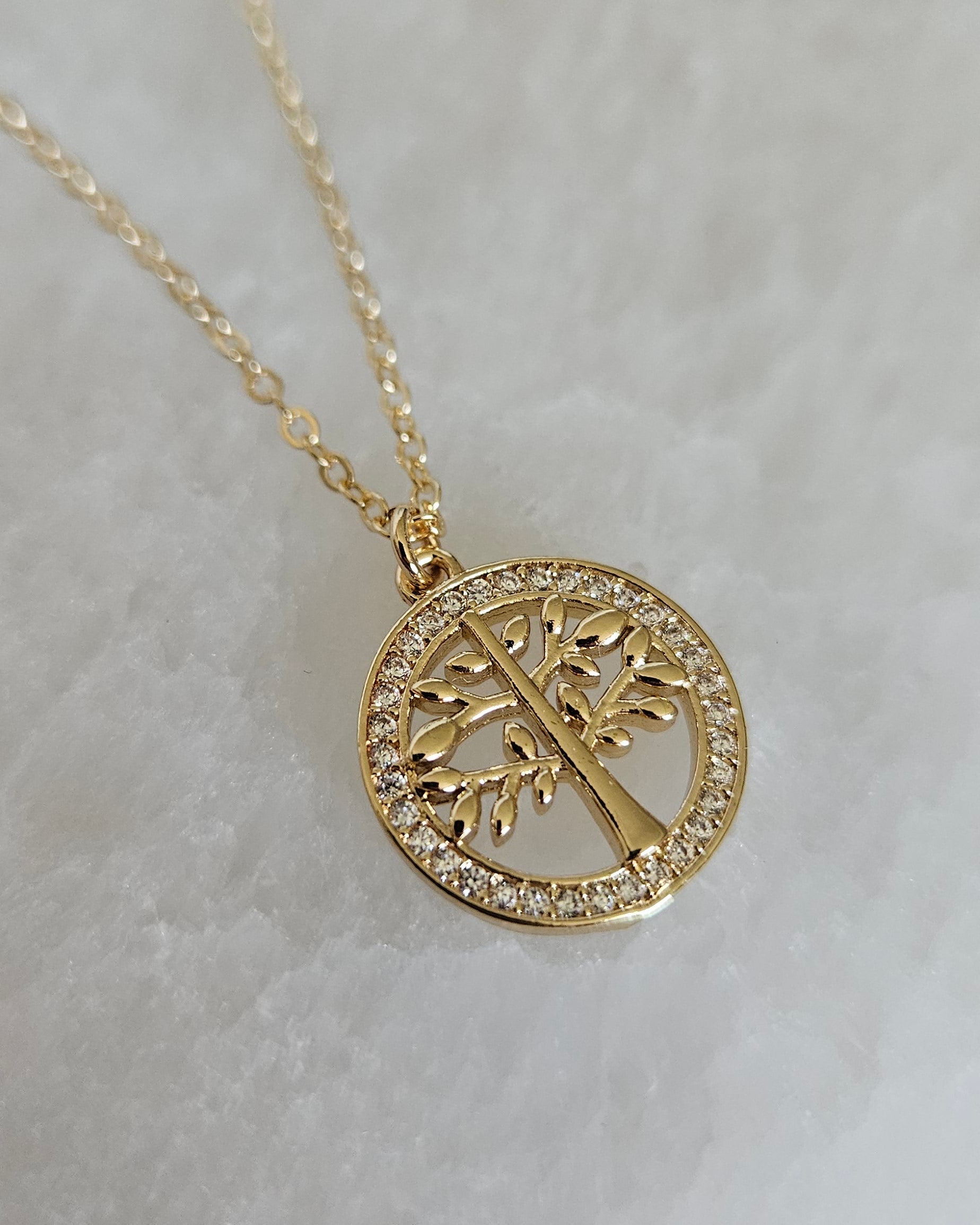 Detailed close-up of the openwork Tree of Life pendant and cubic zirconia border on selenite