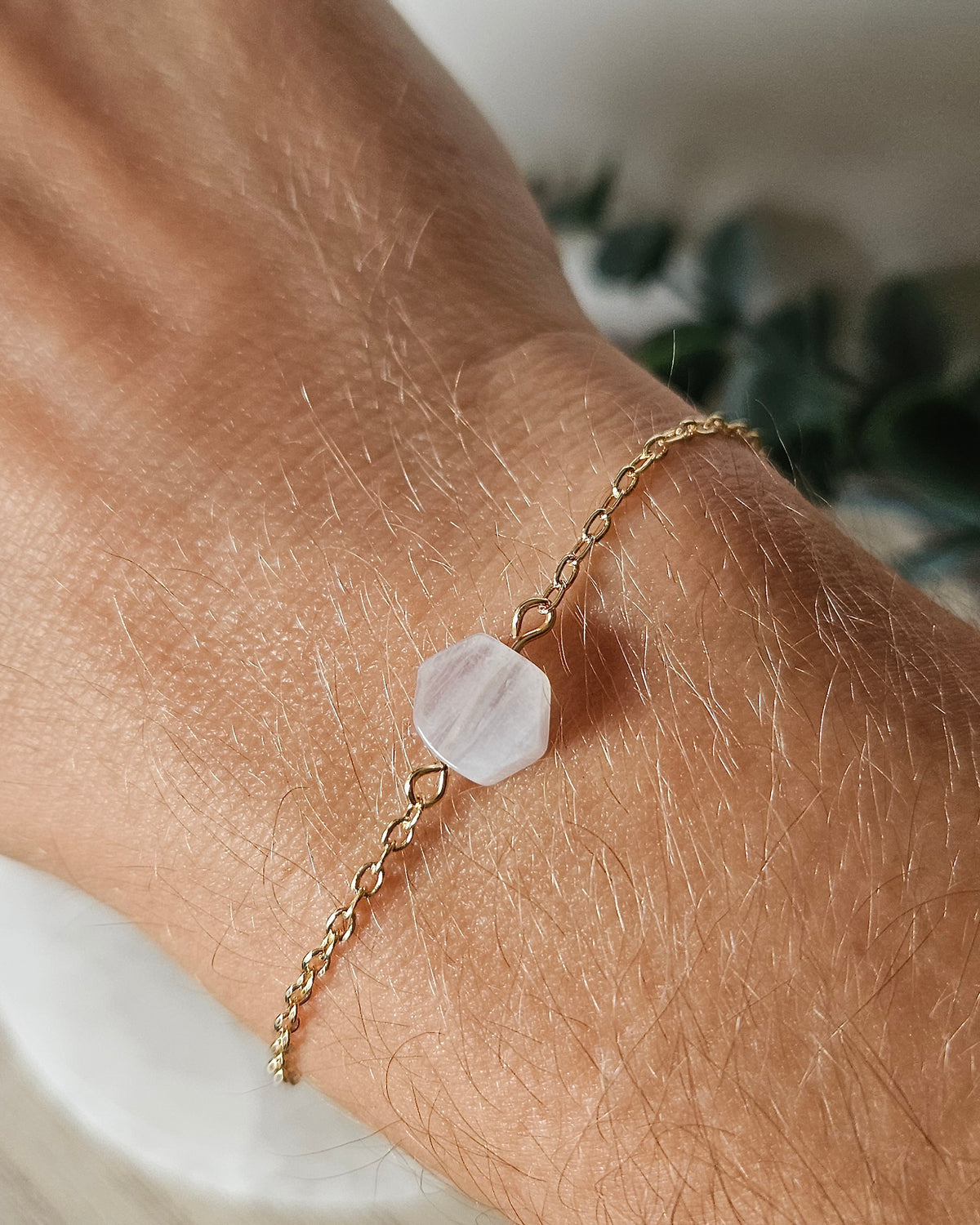 Moonstone Whisper bracelet worn on wrist showing the white hexagon gemstone focal and delicate gold-plated chain