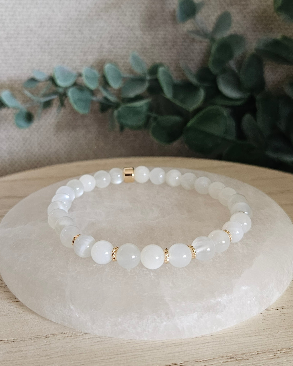 White Moonstone Grace bracelet with creamy white gemstone beads and 14k gold-plated accents displayed on selenite