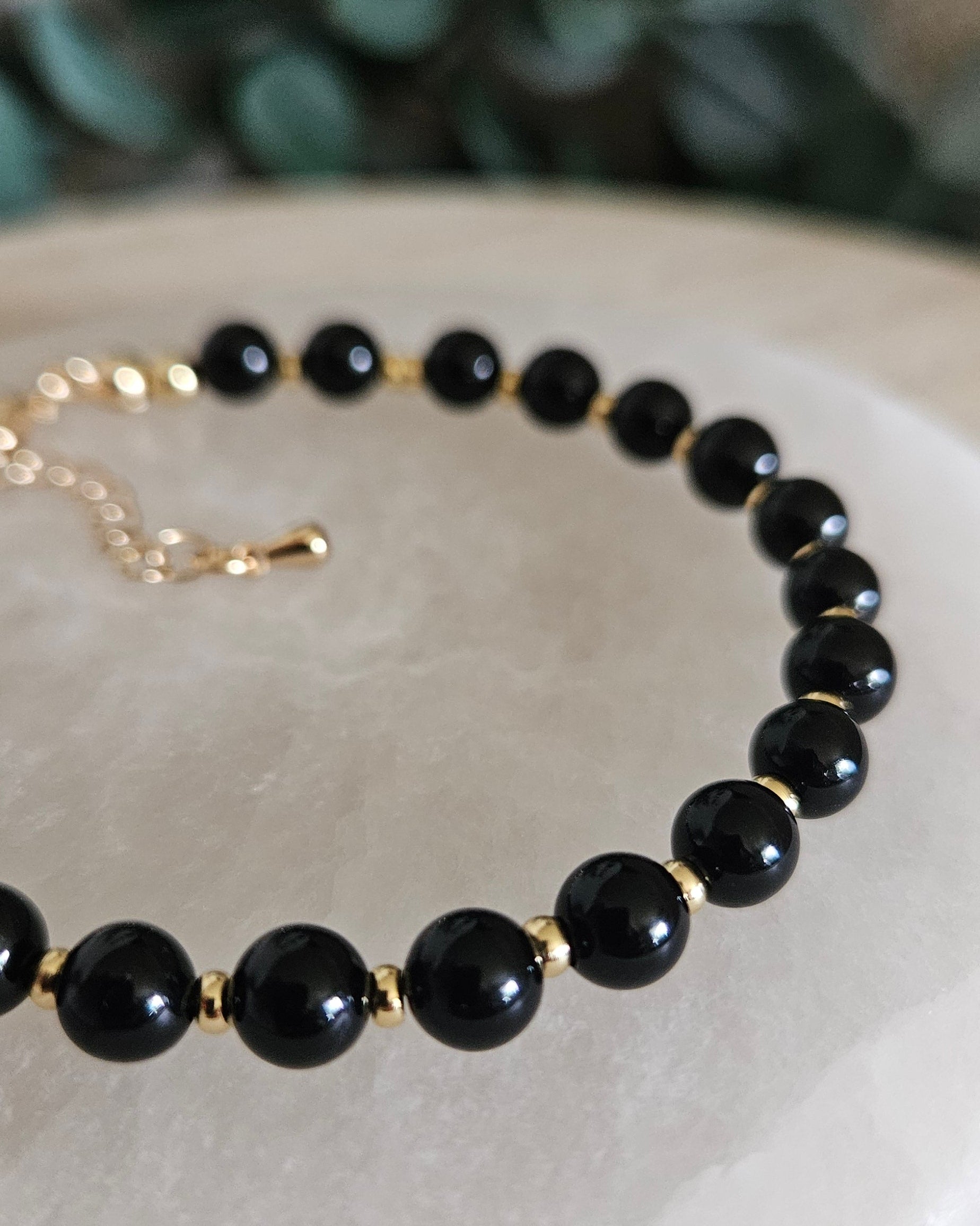 Close-up of glossy Black Onyx beads and gold-plated spacers on the Echo bracelet