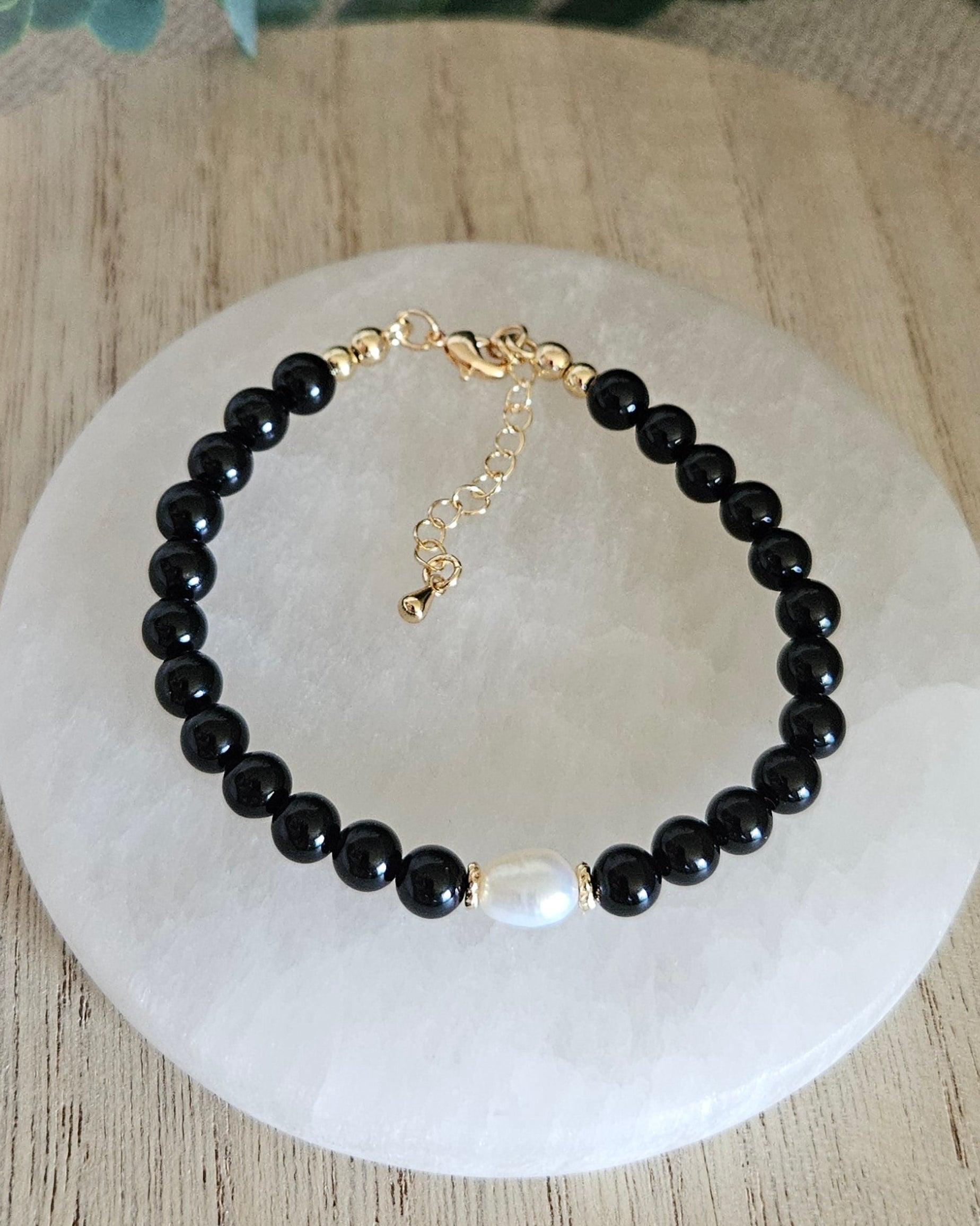 Overhead view of the Black Onyx Embrace bracelet with freshwater pearl focal, clasp and extender chain