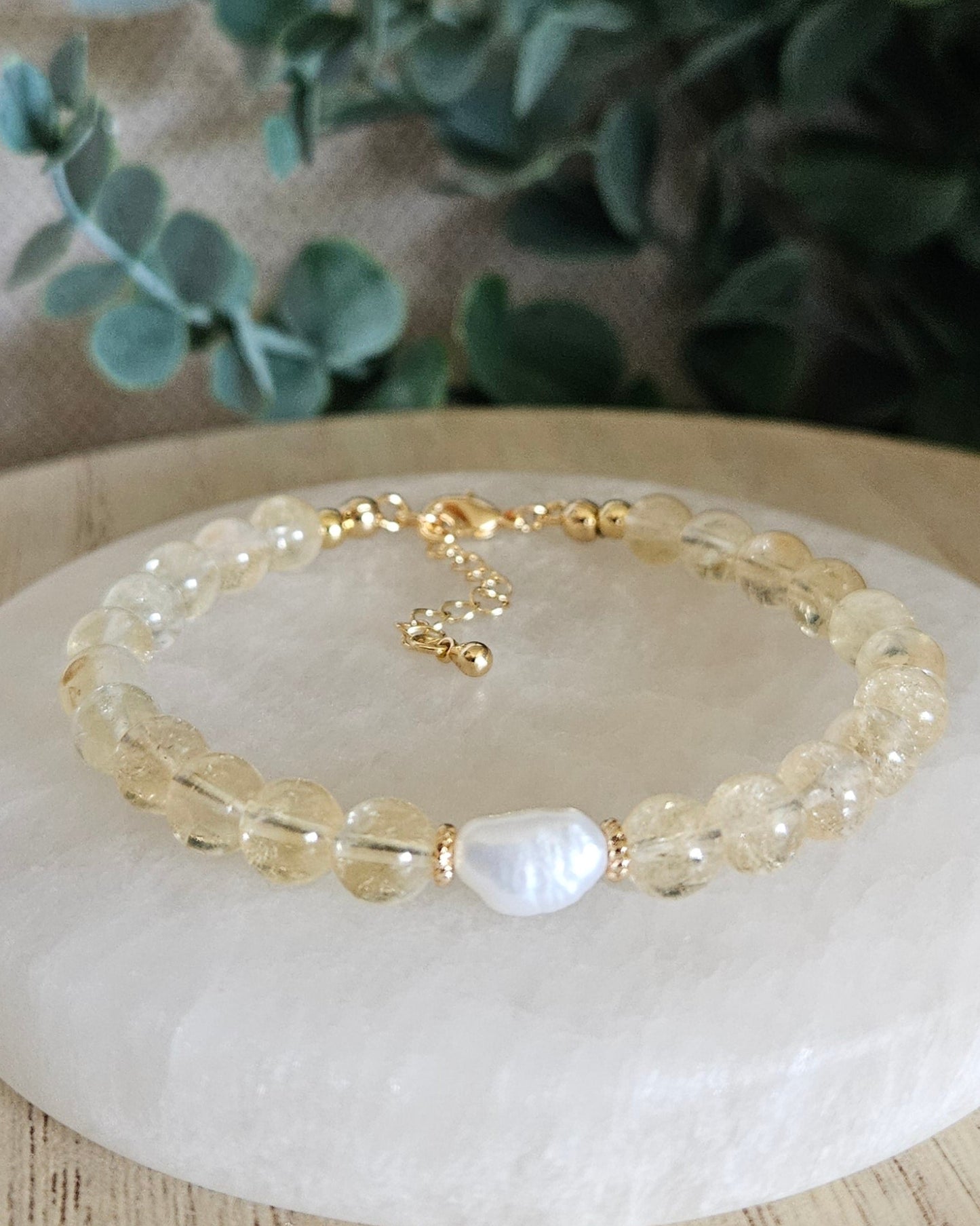Citrine Embrace bracelet with freshwater pearl focal and gold-plated accents displayed on a selenite plate