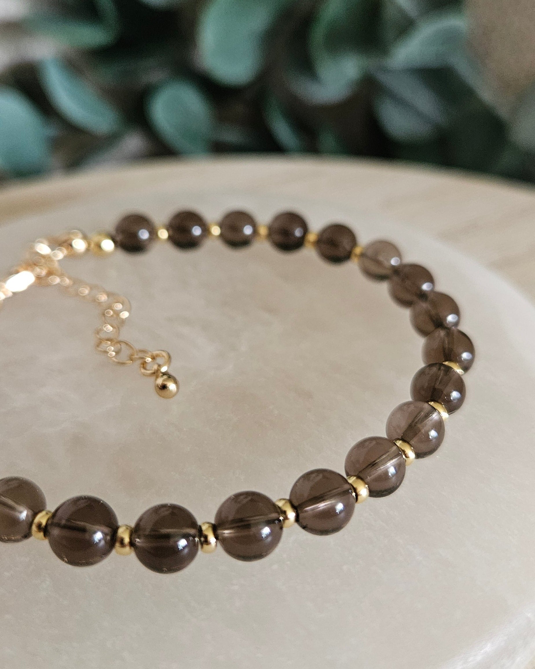 Close-up of translucent brown Smoky Quartz beads and gold-plated spacers on the Echo bracelet