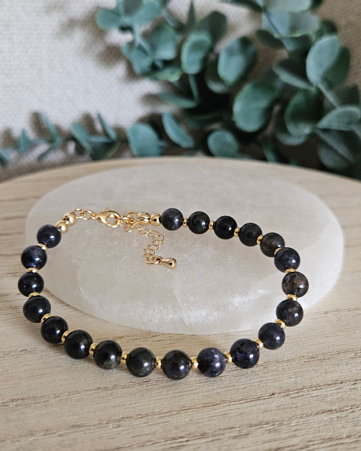 Iolite Echo bracelet arranged before a selenite plate with eucalyptus in the background