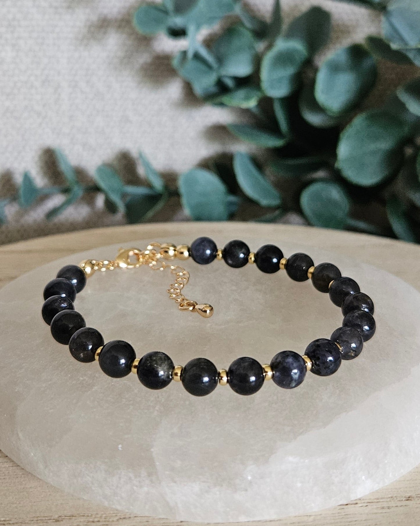 Iolite Echo bracelet with gold-plated accents and clasp displayed on a round selenite plate