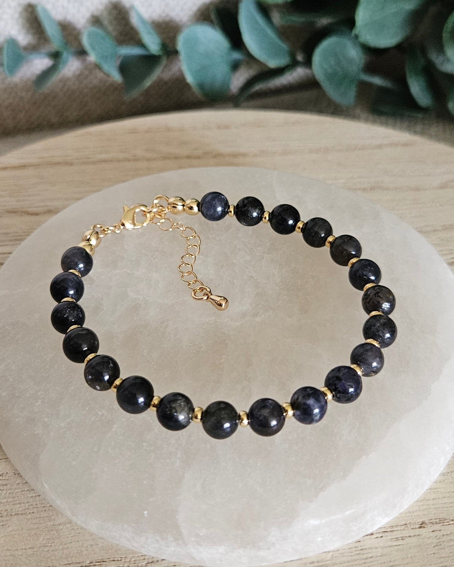 Overhead view of the Iolite Echo bracelet with gold-plated clasp and extender chain on selenite