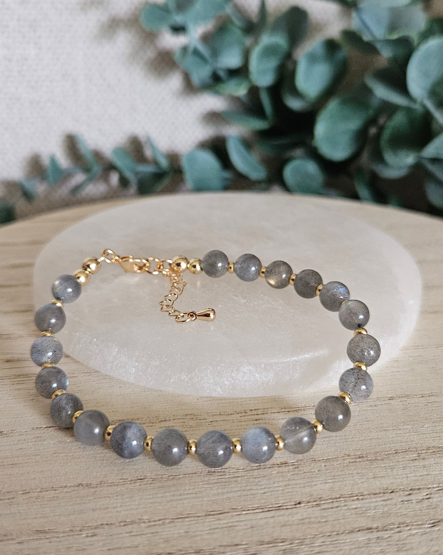 Labradorite Echo bracelet arranged before a selenite plate with eucalyptus in the background