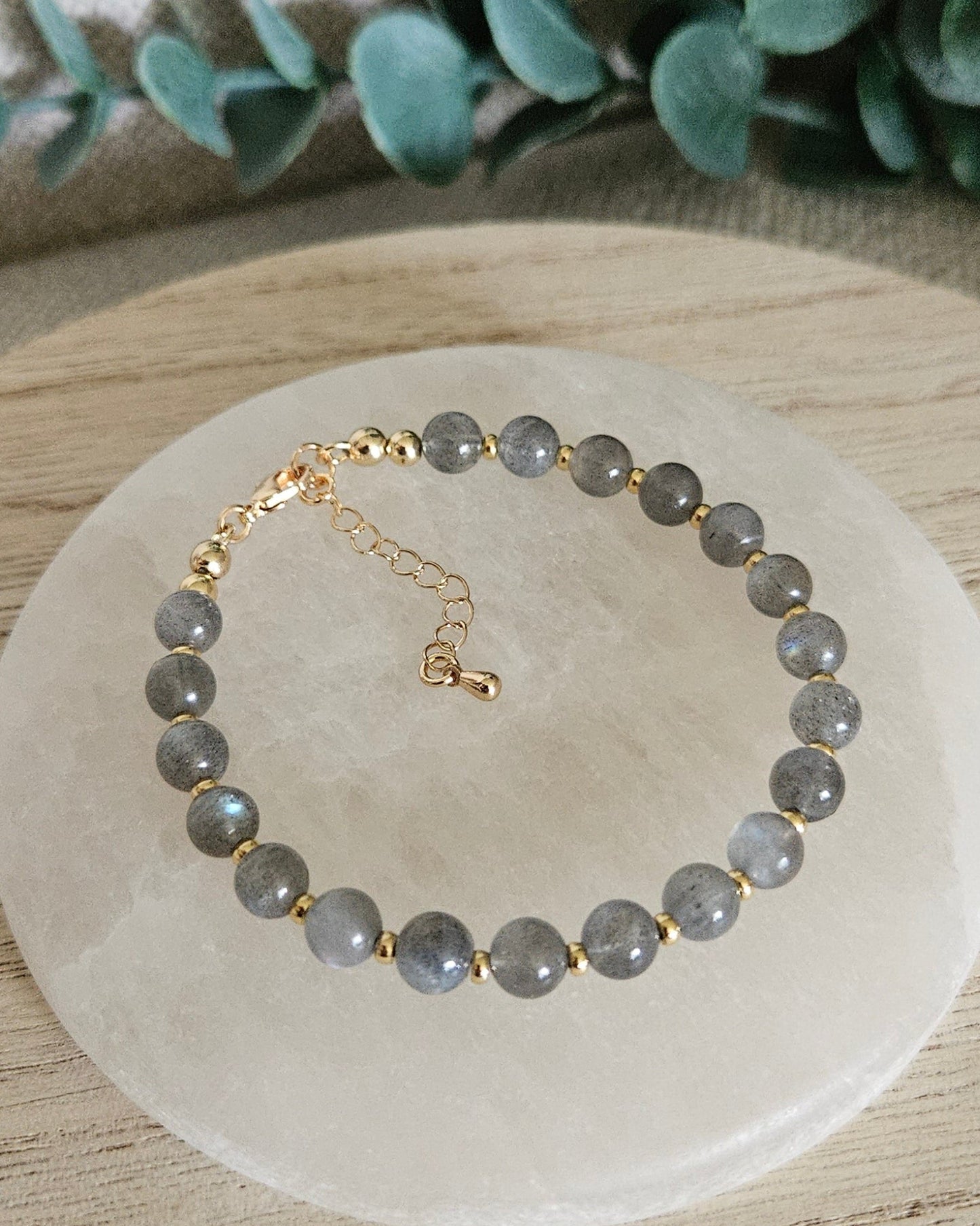 Overhead view of the Labradorite Echo bracelet with gold-plated clasp and extender chain on selenite