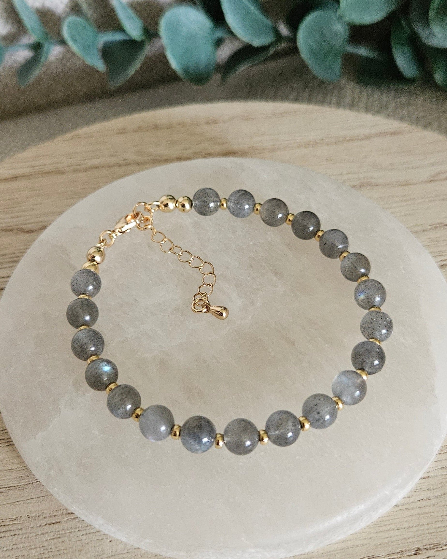 Overhead view of the Labradorite Echo bracelet with gold-plated clasp and extender chain on selenite