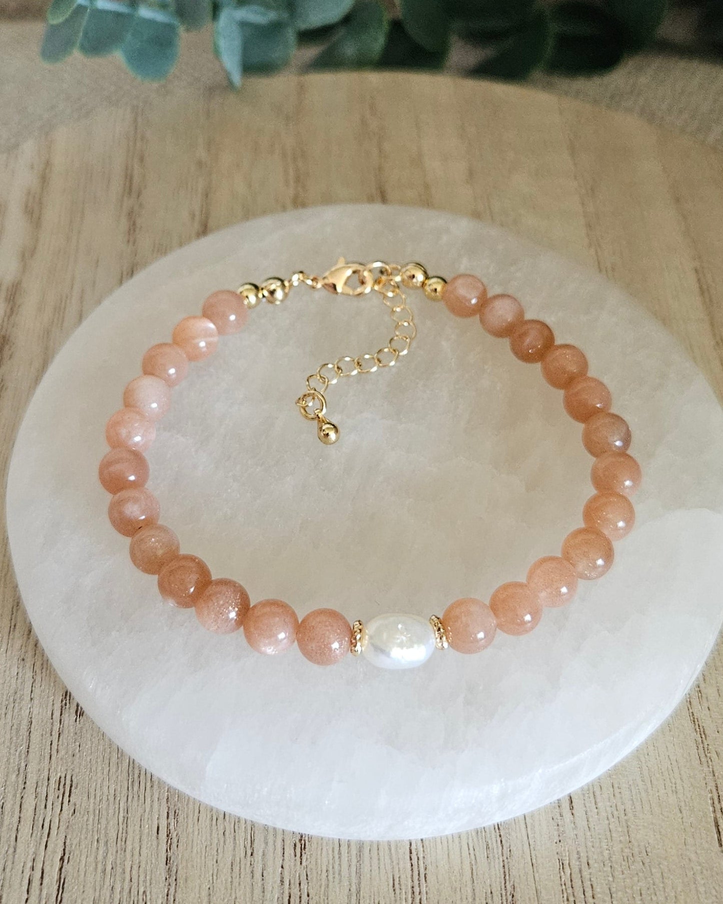 Overhead view of the Sunstone Embrace bracelet with freshwater pearl focal, clasp and extender chain