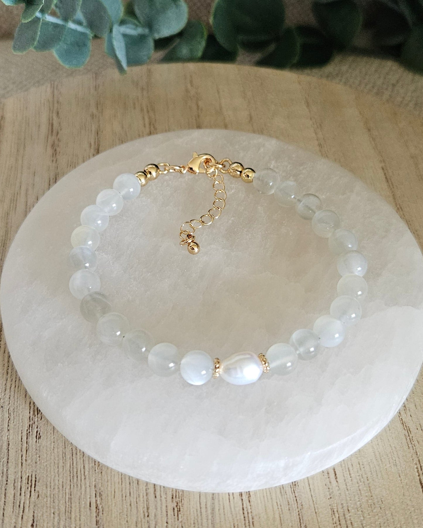 Overhead view of the White Moonstone Embrace bracelet with freshwater pearl focal, clasp and extender chain