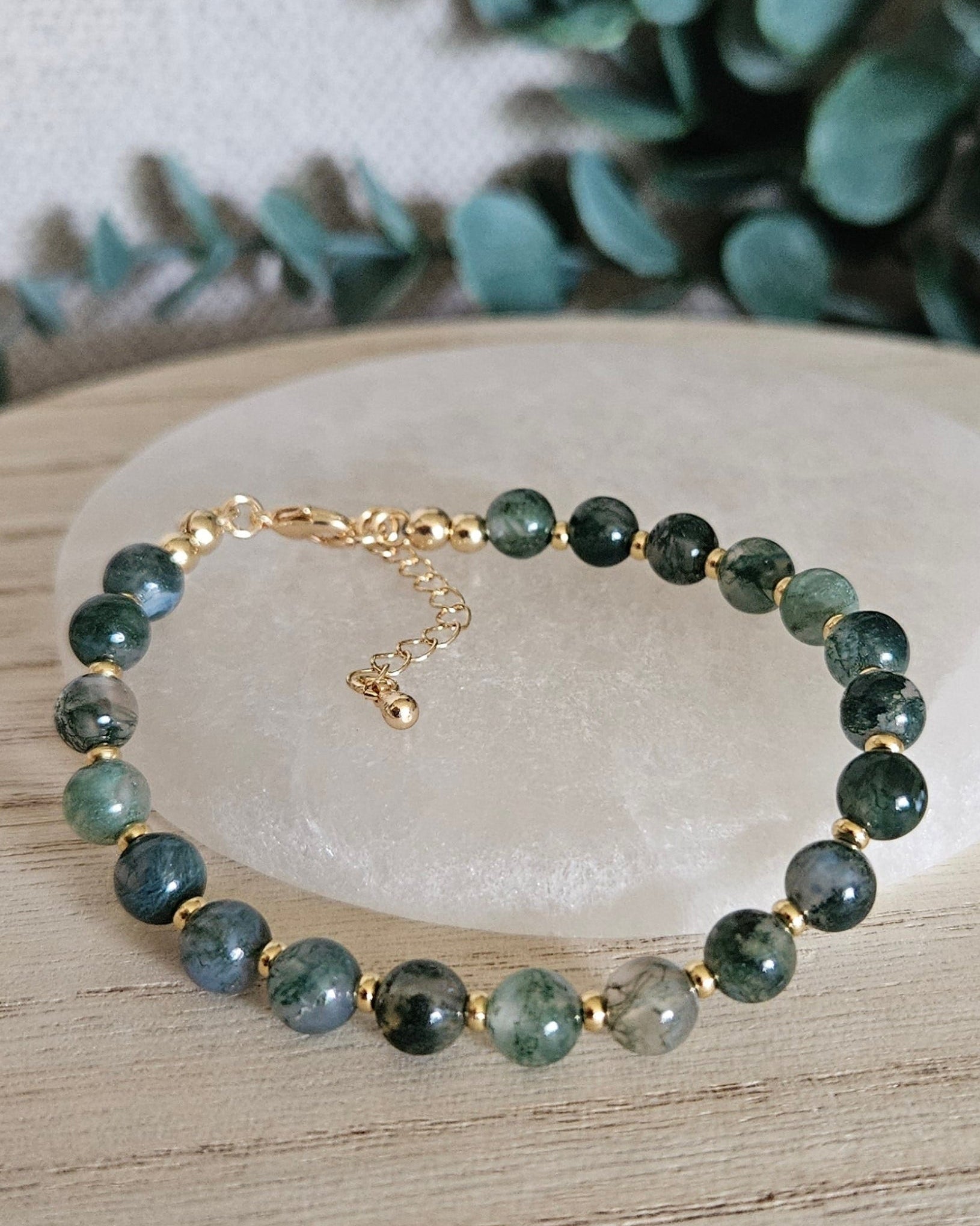 Moss Agate Echo bracelet arranged before a selenite plate with eucalyptus in the background