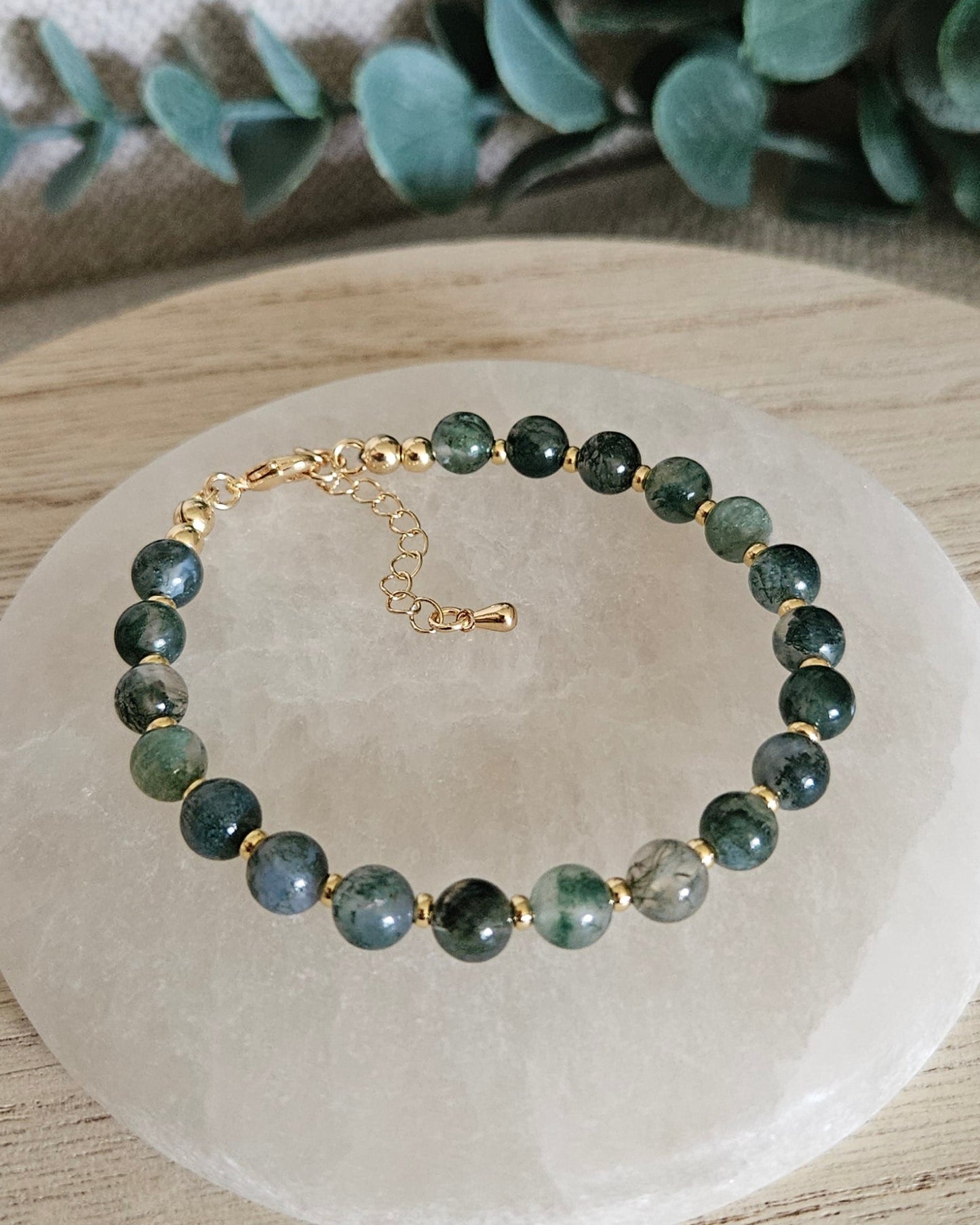 Overhead view of the Moss Agate Echo bracelet with gold-plated clasp and extender chain on selenite