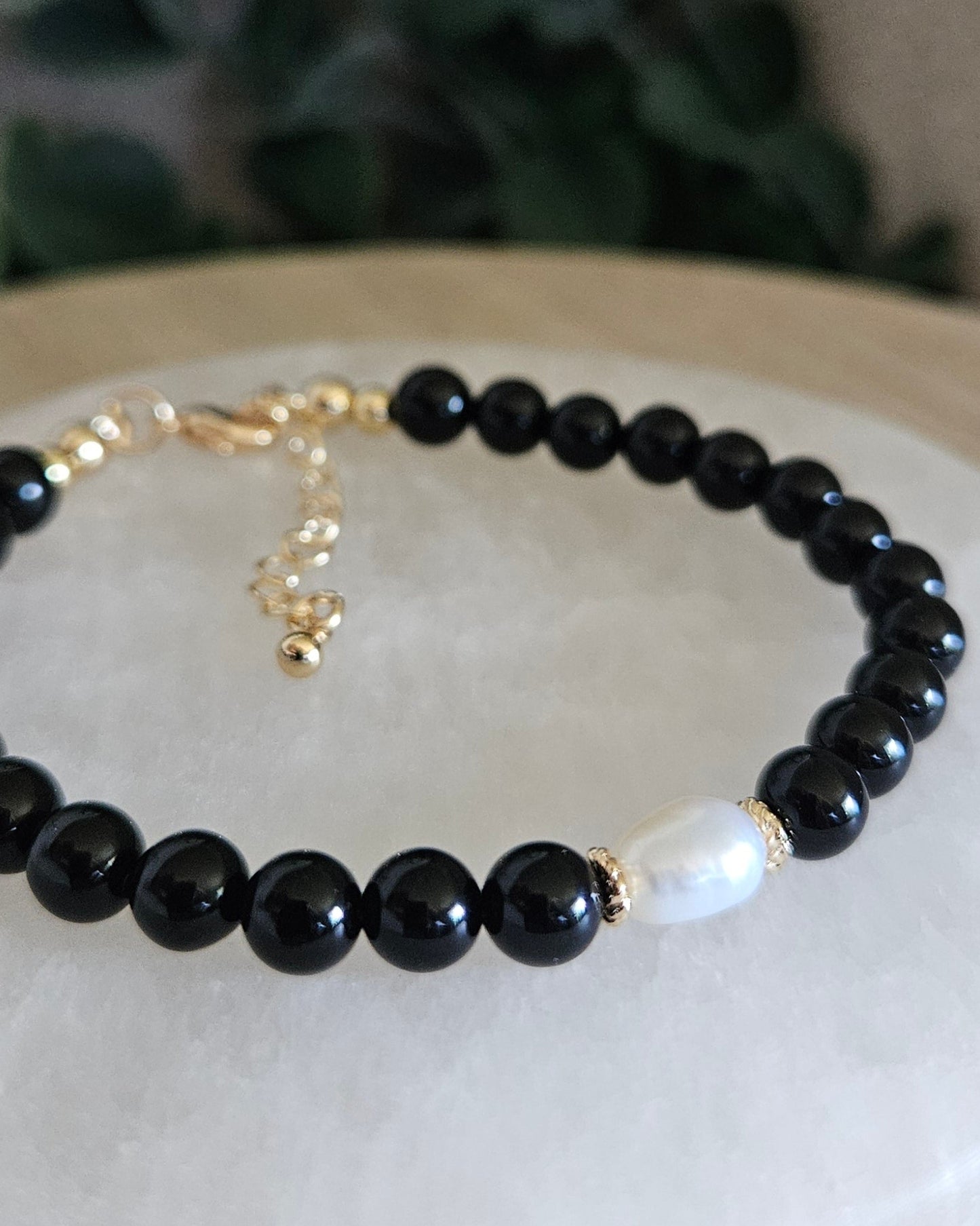 Close-up of Black Onyx beads and a freshwater pearl focal with gold-plated floral spacers
