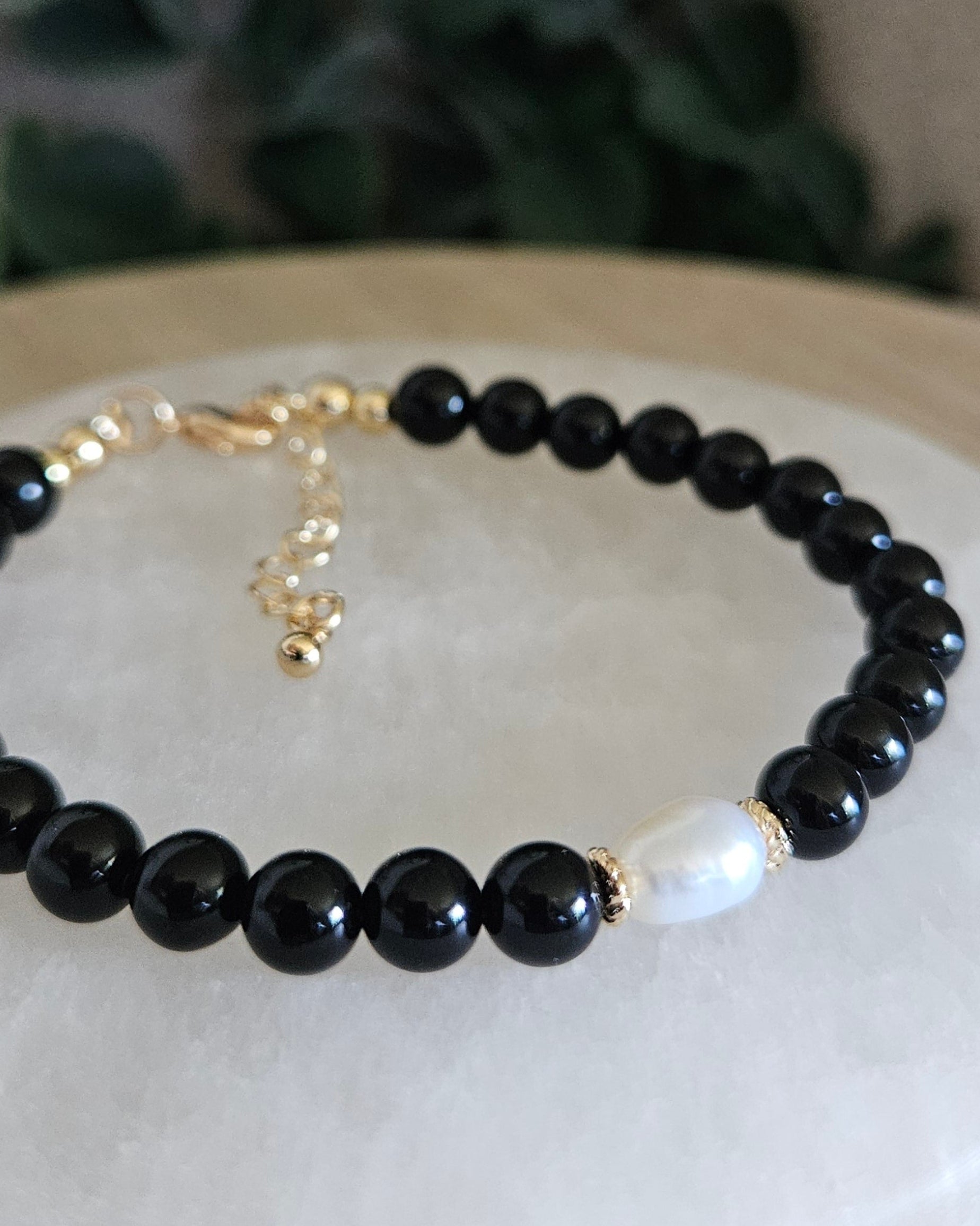 Close-up of Black Onyx beads and a freshwater pearl focal with gold-plated floral spacers