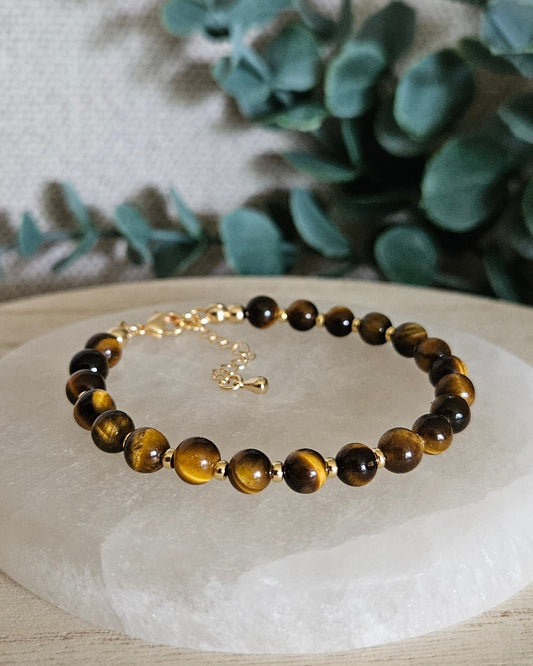 Tiger’s Eye Echo bracelet with gold-plated accents and clasp displayed on a round selenite plate